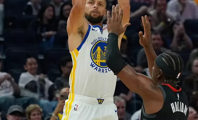 Golden State Warriors guard Stephen Curry, left, shoots a 3-point basket over Houston Rockets guard Aaron Holiday during the first half of an NBA basketball game, Sunday, April 5, 2026, in San Francisco. (AP Photo/Godofredo A. Vásquez)