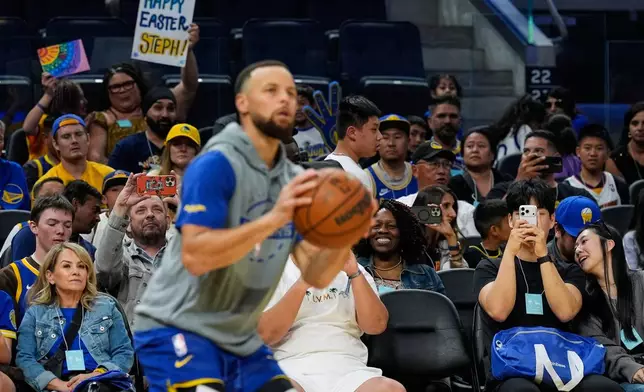 Fans watch as Golden State Warriors guard Stephen Curry, foreground, warms up before an NBA basketball game against the Houston Rockets, Sunday, April 5, 2026, in San Francisco. (AP Photo/Godofredo A. Vásquez)