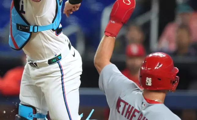 St. Louis Cardinals' JJ Wetherholt scores past Miami Marlins catcher Liam Hicks on a hit by Alec Burleson, during the third inning of a baseball game, Tuesday, April 21, 2026, in Miami. (AP Photo/Rebecca Blackwell)