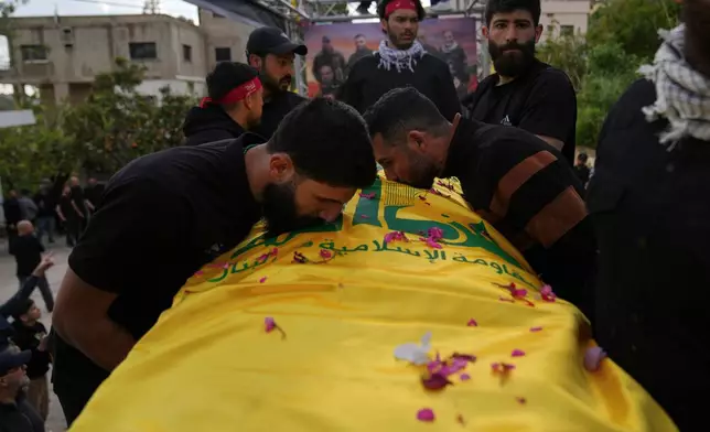 Mourners kiss a coffin of a Hezbollah fighter, who was killed before the ceasefire in the war between Hezbollah and Israel, during a mass funeral procession in the southern village of Kfar Sir, Lebanon, Tuesday, April 21, 2026. (AP Photo/Hassan Ammar)