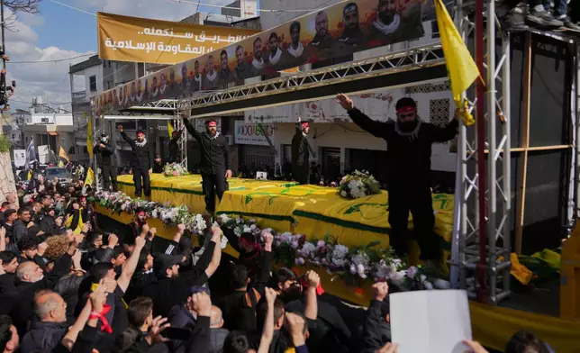 Coffins of Hezbollah fighters killed before the ceasefire in the war between Hezbollah and Israel are carried on a truck past mourners during a mass funeral procession in the southern village of Kfar Sir, Lebanon, Tuesday, April 21, 2026. (AP Photo/Hassan Ammar)