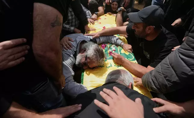 A man mourns over the coffin of a Hezbollah fighter who was killed in the war between Hezbollah and Israel during a mass funeral in Bazouriyeh village, south Lebanon, Monday, April 20, 2026. (AP Photo/Mohammed Zaatari)