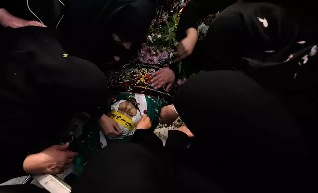 Mourners gather over the body of Jawad Younes, 11, who was killed in an Israeli airstrike during his funeral procession in Saksakieh village, south Lebanon, Saturday, March 28, 2026. (AP Photo/Hussein Malla)