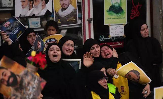 Mourners grieve during a mass funeral procession of Hezbollah fighters who were killed before the ceasefire in the war between Hezbollah and Israel, in the southern village of Kfar Sir, Lebanon, Tuesday, April 21, 2026. (AP Photo/Hassan Ammar)