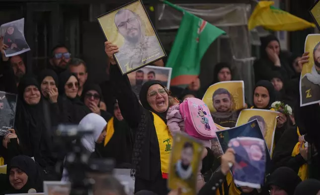 A woman mourns while holding a portrait of a Hezbollah fighter killed before the ceasefire in the war between Hezbollah and Israel during a mass funeral procession in the southern village of Kfar Sir, Lebanon, Tuesday, April 21, 2026. (AP Photo/Hassan Ammar)