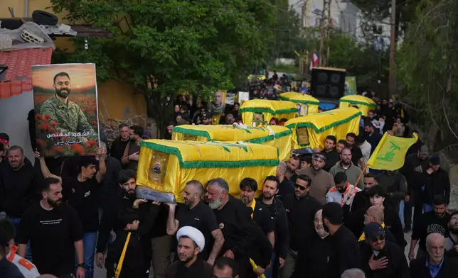 Mourners carry the coffins of Hezbollah fighters killed before the ceasefire in the war between Hezbollah and Israel during a mass funeral procession in the southern village of Kfar Sir, Lebanon, Tuesday, April 21, 2026. (AP Photo/Hassan Ammar)