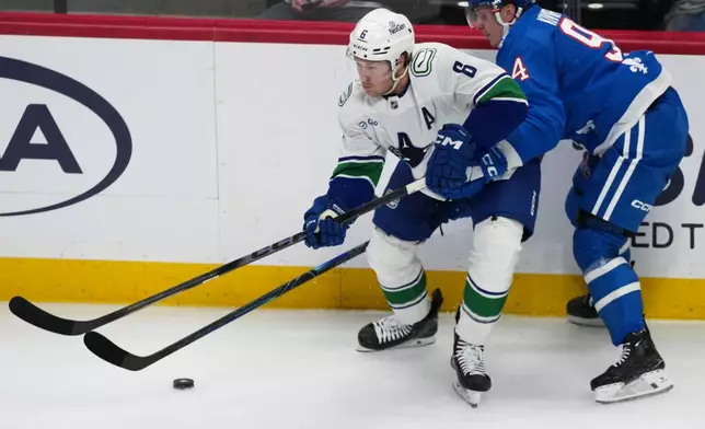 Vancouver Canucks right wing Brock Boeser, left, collects the puck as Colorado Avalanche left wing Joel Kiviranta defends in the second period of an NHL hockey game, Wednesday, April 1, 2026, in Denver. (AP Photo/David Zalubowski)