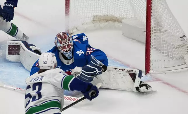 Vancouver Canucks center Teddy Blueger, front, scores a goal past Colorado Avalanche goaltender MacKenzie Blackwood in the first period of an NHL hockey game, Wednesday, April 1, 2026, in Denver. (AP Photo/David Zalubowski)