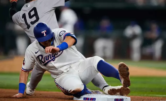 New York Yankees third baseman Ryan McMahon (19) keeps his foot on the bag as he catches the throw on a close play at third where Texas Rangers' Josh Jung, front, was called out on the play in the eighth inning of a baseball game Tuesday, April 28, 2026, in Arlington, Texas. (AP Photo/Tony Gutierrez)