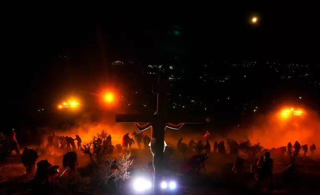 David Sanchez, playing the role of Jesus Christ, hangs on a cross in a Way of the Cross reenactment as part of Holy Week celebrations, in Colina, Chile, on Good Friday, April 3, 2026. (AP Photo/Esteban Felix)