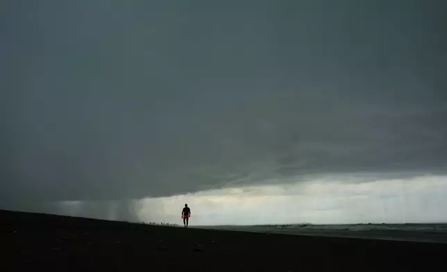 A man walks on the beach as a rain storm moves in to Mar de las Pampas, Argentina, Friday, April 3, 2026. (AP Photo/Rodrigo Abd)