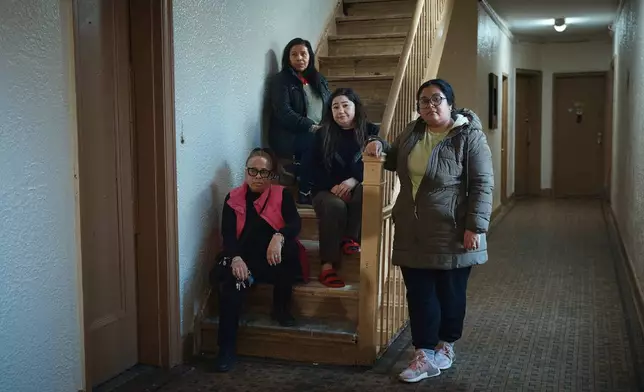 Gulhayo Yuldosheva, 33 , center right, Marina Quiroz, 65, top, pose for a portrait with other two residents in an apartment building where tenants report maintenance issues and pest infestations, in the Bronx borough of New York, Tuesday, March 17, 2026. (AP Photo/Andres Kudacki)