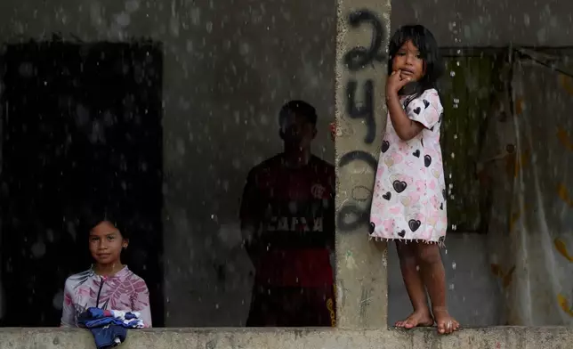 Children watch from the balcony of their house in an area known as Nova Conquista or New Conquest where families are building houses near the center of Oiapoque, Amapa state, Brazil, Tuesday, March 10, 2026. (AP Photo/Eraldo Peres)