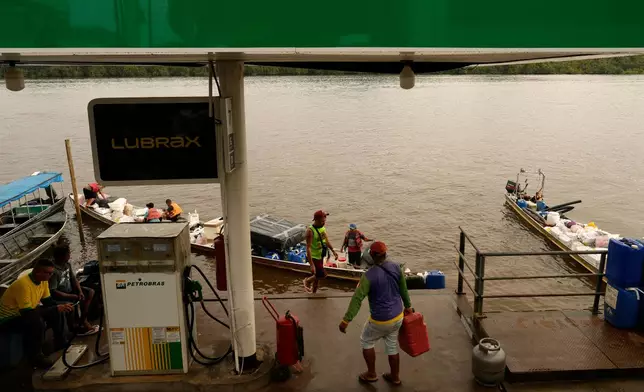 Boatmen operating Catraia, a traditional boat used on the Oiapoque River, prepare for the crossing with a load of gasoline canisters filled at a Petrobras gas station in a port in the city of Oiapoque, Amapa state, Brazil, Tuesday, March 10, 2026. (AP Photo/Eraldo Peres)