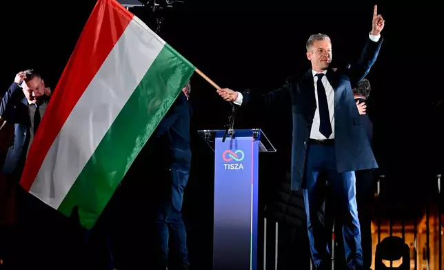 Peter Magyar, leader of the opposition Tisza party, waves the Hungarian flag following the announcement of the partial results of the parliamentary election, in Budapest, Hungary, Sunday, April 12, 2026. (AP Photo/Denes Erdos)