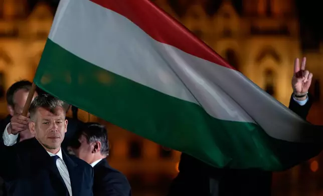 Peter Magyar, the leader of the opposition Tisza party waves a national flag after claiming victory in a parliamentary election in Budapest, Hungary, Sunday, April 12, 2026. (AP Photo/Darko Bandic)
