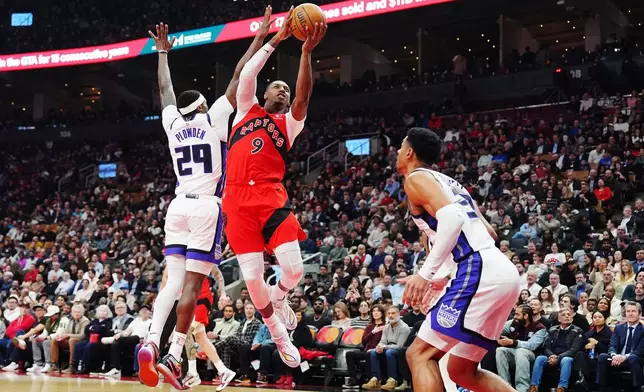 Toronto Raptors' RJ Barrett (9) leaps past Sacramento Kings' Daeqwon Plowden (29) as Dylan Cardwell (32) defends during the first half of an NBA basketball game in Toronto on Wednesday, April 1, 2026. (Frank Gunn/The Canadian Press via AP)