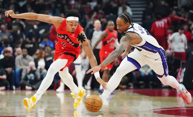 Toronto Raptors' Scottie Barnes (4) and Sacramento Kings' DeMar DeRozan (10) battle for the ball during the first half of an NBA basketball game in Toronto, Wednesday, April 1, 2026. (Frank Gunn/The Canadian Press via AP)