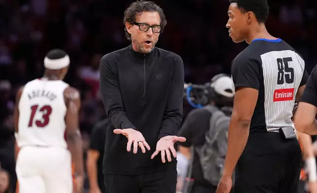 Atlanta Hawks head coach Quin Snyder, center, talks with referee Robert Hussey (85) during the first half of an NBA basketball game against the Miami Heat, Sunday, April 12, 2026, in Miami. (AP Photo/Rebecca Blackwell)