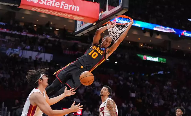 Atlanta Hawks forward Zaccharie Risacher (10) dunks over Miami Heat forward Jaime Jaquez Jr., left as Miami Heat center Kel'el Ware looks on during the first half of an NBA basketball game, Sunday, April 12, 2026, in Miami. (AP Photo/Rebecca Blackwell)