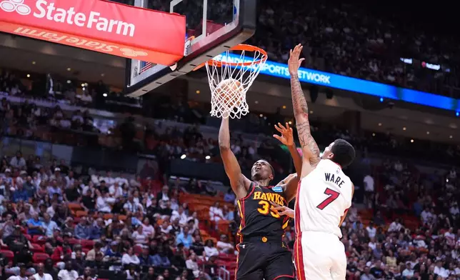 Atlanta Hawks center Christian Koloko (35) scores defended by Miami Heat center Kel'el Ware (7) during the first half of an NBA basketball game, Sunday, April 12, 2026, in Miami. (AP Photo/Rebecca Blackwell)