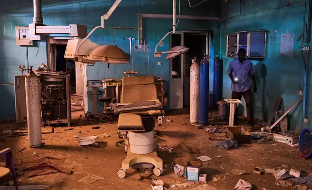 A guard walks through a war-damaged section of Al Shaabi Hospital in Khartoum, Saturday, April 18, 2026. (AP Photo/Bernat Armangue)