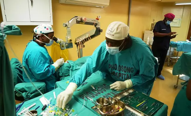 An ophthalmologist performs cataract surgery while an assistant hands him surgical instruments during a marathon event, in Tsakane, South Africa, Saturday, March 28, 2026. (AP Photo/Kayleen Morgan)