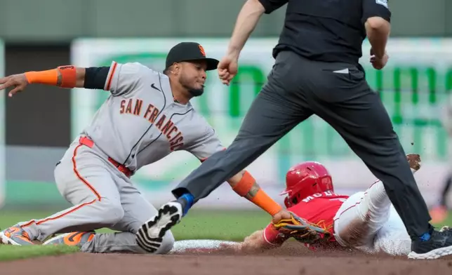 Cincinnati Reds' Matt McLain, right, is caught stealing second base by San Francisco Giants shortstop Willy Adames, left, as umpire Junior Valentine moves in during the first inning of a baseball game in Cincinnati, Tuesday, April 14, 2026. (AP Photo/Carolyn Kaster)