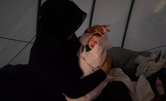 Haifa Kenjo, who fled Israeli airstrikes on the southern suburbs of Beirut, holds her 15-day-old daughter Shiman inside the tent she uses as a shelter and where she gave birth to her in Beirut, Sunday, April 12, 2026. (AP Photo/Emilio Morenatti)