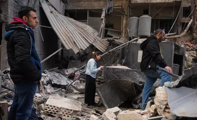 Residents inspect debris at the site of a building where efforts continue to recover the body of missing woman Zahraa Aboud, 26, after it was destroyed in an Israeli airstrike on Wednesday, in central Beirut, Sunday, April 12, 2026. (AP Photo/Hassan Ammar)