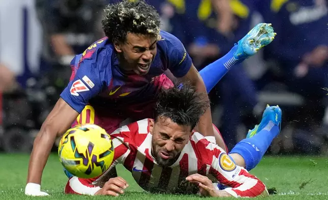 Barcelona's Lamine Yamal, top, is tackled and fouled by Atletico Madrid's Nico Gonzalez, who receives a second yellow card and is then sent off during a La Liga soccer match between Atletico Madrid and Barcelona in Madrid, Spain, Saturday, April 4, 2026. (AP Photo/Bernat Armangue)