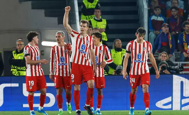 Atletico Madrid's Alexander Sorloth, centre, celebrates after scoring his side's second goal during the Champions League quarterfinal first leg soccer match between Barcelona and Atletico Madrid in Barcelona, Spain, Wednesday, April 8, 2026. (AP Photo/Joan Monfort)