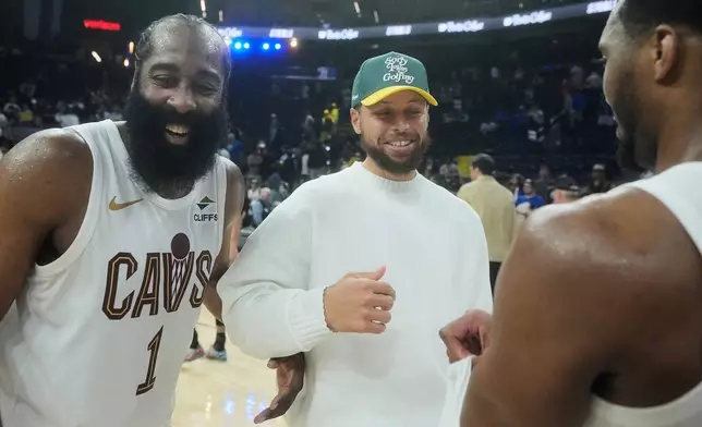 Injured Golden State Warriors guard Stephen Curry, middle, smiles while talking with Cleveland Cavaliers guard James Harden (1) and guard Donovan Mitchell after an NBA basketball game in San Francisco, Thursday, April 2, 2026. (AP Photo/Jeff Chiu)