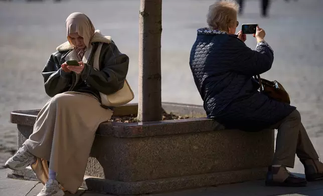 Women hold their cellphones in Red Square, in Moscow, Wednesday, March 11, 2026. (AP Photo/Alexander Zemlianichenko)