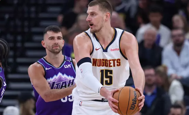 Denver Nuggets center Nikola Jokic (15) holds the ball away from Utah Jazz guard John Konchar during the first half of an NBA basketball game, Wednesday, April 1, 2026, in Salt Lake City. (AP Photo/Rob Gray)