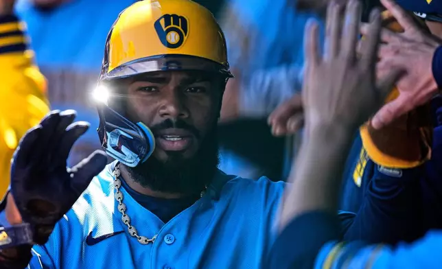 Milwaukee Brewers' Luis Rengifo celebrates in the dugout after scoring on a double by Garrett Mitchell during the first inning in the first baseball game of a doubleheader against the Kansas City Royals, Saturday, April 4, 2026, in Kansas City, Mo. (AP Photo/Charlie Riedel)