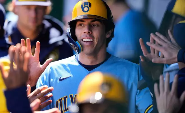 Milwaukee Brewers' Christian Yelich celebrates in the dugout after scoring on a double by Garrett Mitchell during the first inning in the first baseball game of a doubleheader against the Kansas City Royals, Saturday, April 4, 2026, in Kansas City, Mo. (AP Photo/Charlie Riedel)