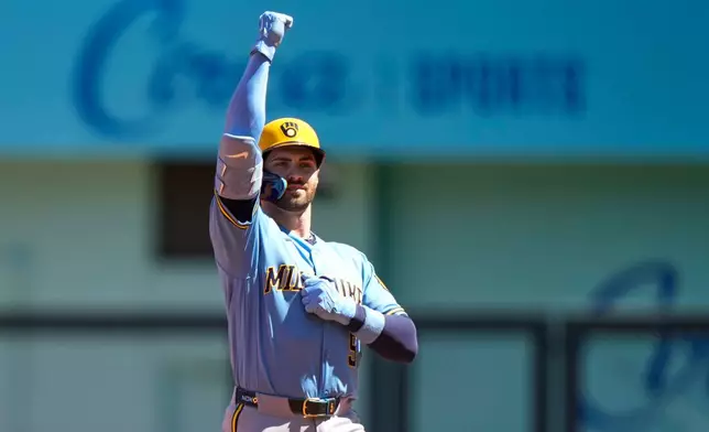 Milwaukee Brewers' Garrett Mitchell celebrates on second after hitting a two-run double during the first inning in the first baseball game of a doubleheader against the Kansas City Royals, Saturday, April 4, 2026, in Kansas City, Mo. (AP Photo/Charlie Riedel)