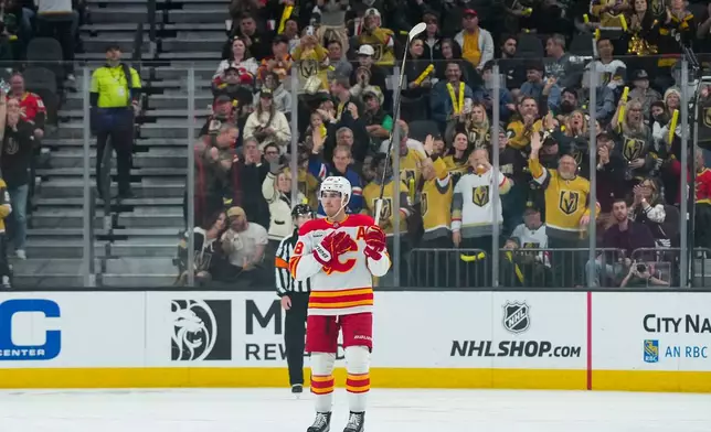 Calgary Flames defenseman Zach Whitecloud, center, salutes the fans during the first period of an NHL hockey game against the Vegas Golden Knights, Thursday, April 2, 2026, in Las Vegas. (AP Photo/Candice Ward)