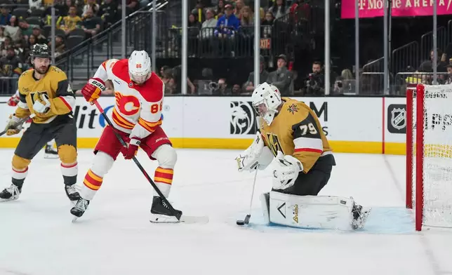 Vegas Golden Knights goaltender Carter Hart (79) stops a shot behind Calgary Flames left wing Joel Farabee (86) during the first period of an NHL hockey game Thursday, April 2, 2026, in Las Vegas. (AP Photo/Candice Ward)