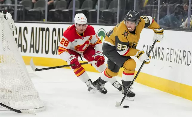Vegas Golden Knights right wing Mitch Marner (93) skates with the puck against Calgary Flames defenseman Zach Whitecloud (28) during the second period of an NHL hockey game Thursday, April 2, 2026, in Las Vegas. (AP Photo/Candice Ward)