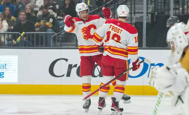 Calgary Flames center John Beecher (18) celebrates after his goal with defenseman Zayne Parekh (19) during the first period of an NHL hockey game against the Vegas Golden Knights, Thursday, April 2, 2026, in Las Vegas. (AP Photo/Candice Ward)