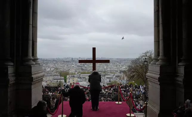 The cross is presented to the faithful during the Way of Cross ceremony to mark Good Friday, outside the Sacre Coeur basilica, Friday, April 3, 2026 . (AP Photo/Thibault Camus)