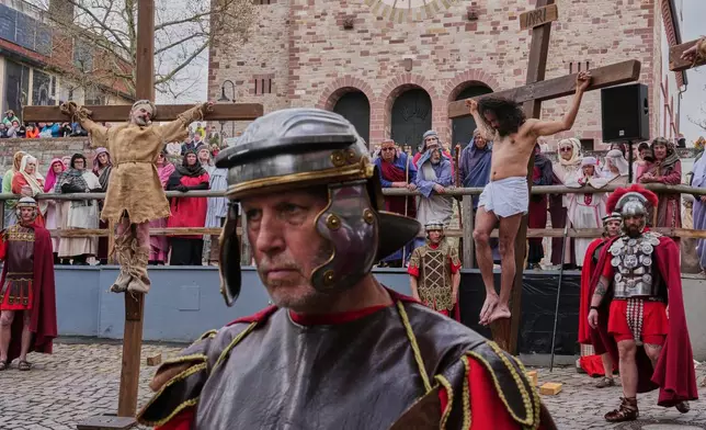 An amateur actor performing as Jesus, right, is fixed on a cross during the traditional Good Friday procession organised by the Italian community in Bensheim, Germany, Friday, April 3, 2026. (AP Photo/Michael Probst)