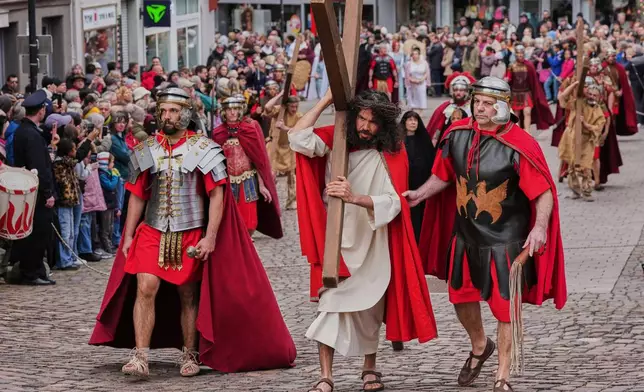 An amateur actor performing as Jesus carries the cross during the traditional Good Friday procession organised by the Italian community in Bensheim, Germany, Friday, April 3, 2026. (AP Photo/Michael Probst)