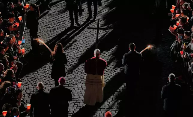 Pope Leo XIV carries a lightweight, 1.5-meter (5-foot) wooden cross during the Via Crucis, the torchlit Good Friday Stations of the Cross procession at the Colosseum in Rome, Friday, April 3, 2026, which symbolically retraces Jesus Christ's steps to his crucifixion on Calvary in Jerusalem. (AP Photo/Alessandra Tarantino)