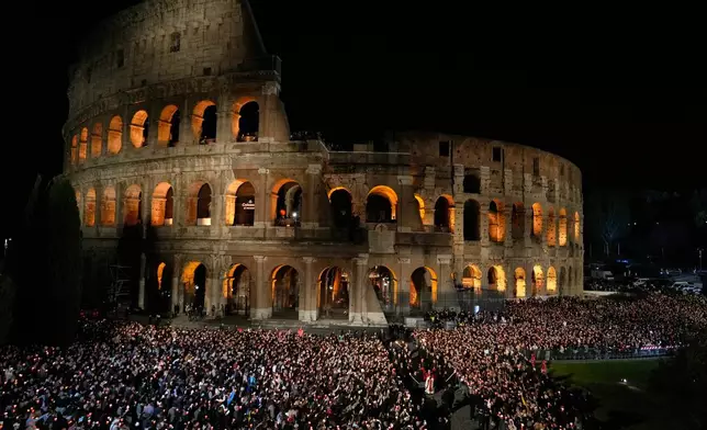 Pope Leo XIV carries a lightweight, 1.5-meter (5-foot) wooden cross during the Via Crucis, the torchlit Good Friday Stations of the Cross procession at the Colosseum in Rome, Friday, April 3, 2026, which symbolically retraces Jesus Christ's steps to his crucifixion on Calvary in Jerusalem. (AP Photo/Gregorio Borgia)
