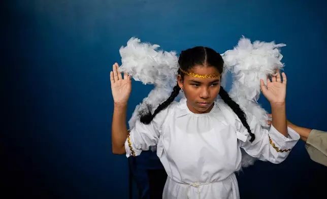 A devotee in an angel costume prepares for the Way of the Cross procession on Good Friday during Holy Week in Arraijan, Panama, Friday, April 3, 2026. (AP Photo/Matias Delacroix)