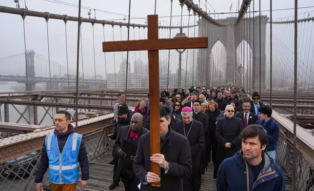 A man carries a cross during the "Way of the Cross" over the Brooklyn Bridge on Good Friday, Friday, April 3, 2026, in New York. (AP Photo/Ryan Murphy)
