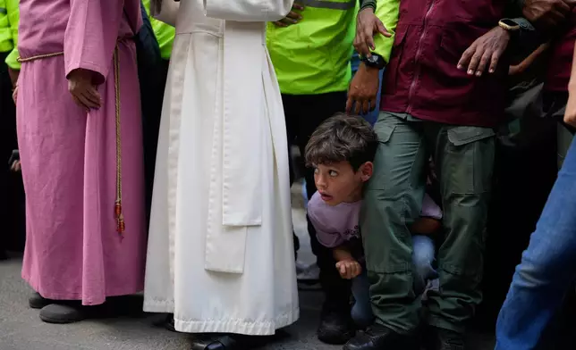 A boy watches a Way of the Cross reenactment as part of Holy Week celebrations in the Petare neighborhood of Caracas, Venezuela, Friday, April 3, 2026. (AP Photo/Ariana Cubillos)